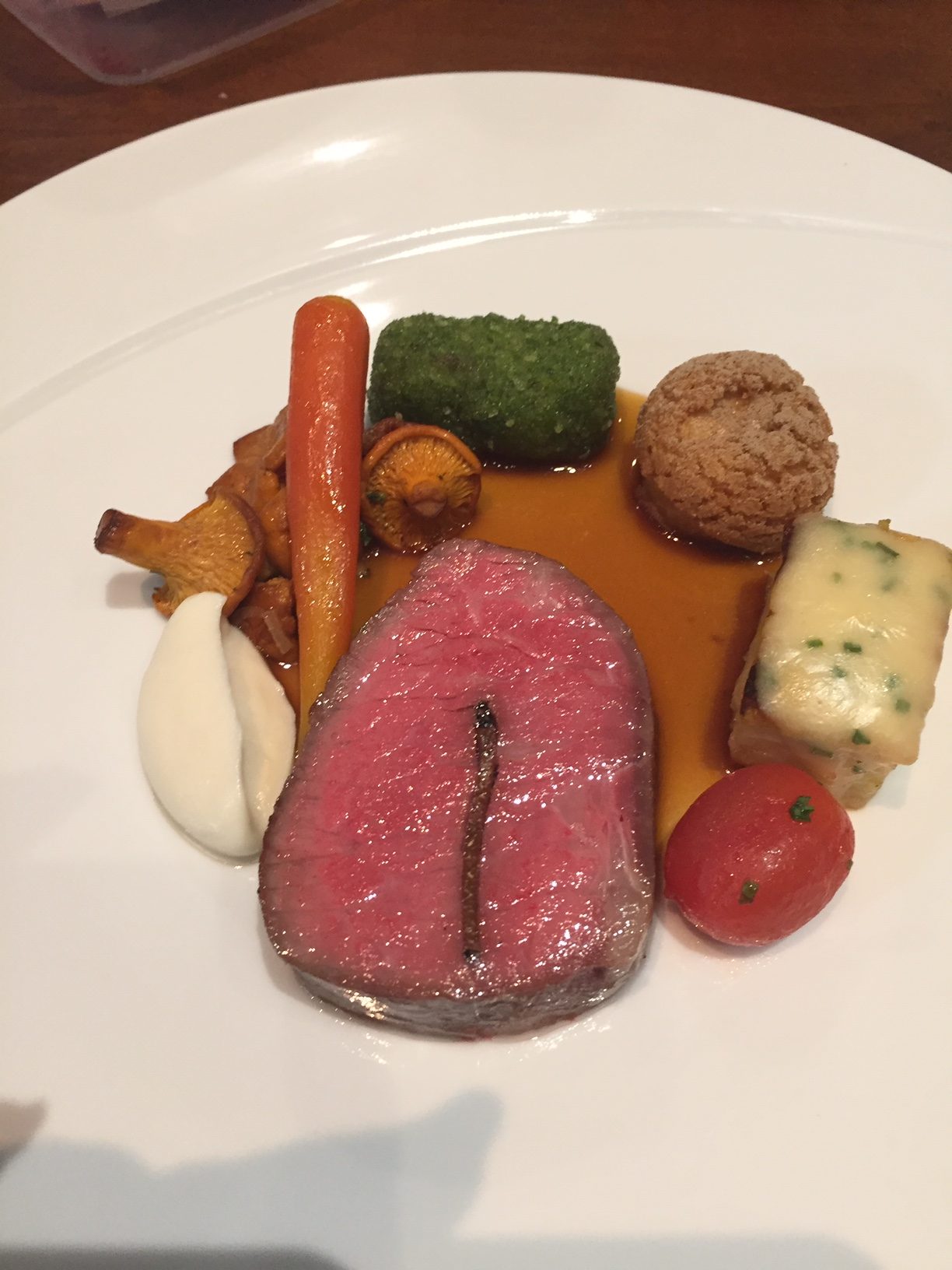 Truffled Canadian beef striploin, potato pave, foie gras profiterole, herbed beef cheek, chantarelles, poached tomato baby carrot